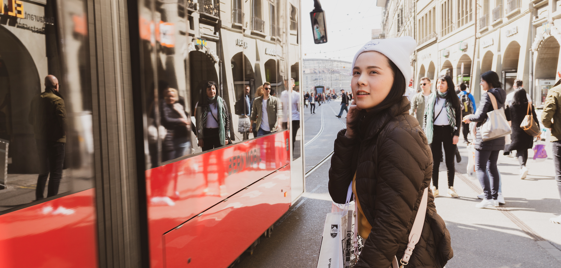 Ein weiblicher Teenager schaut einer vorbeifahrenden, roten Straßenbahn nach.